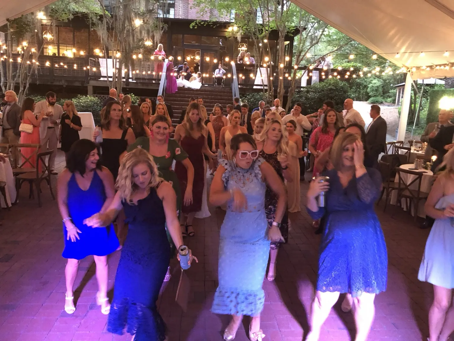 Wedding guests celebrating together beneath string lights at an outdoor reception